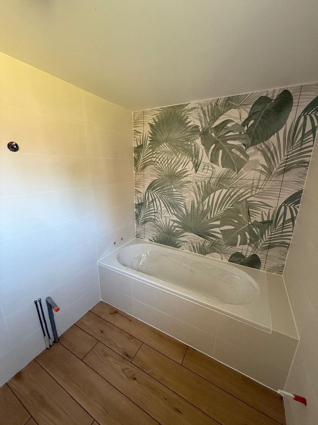 Baignoire avec tablier carrelé imitation bois et papier peint végétal